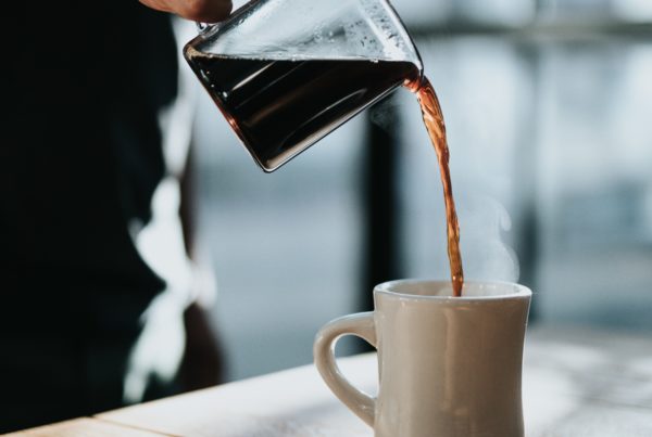 Kaffekanne med kaffe fyller opp kaffekopp