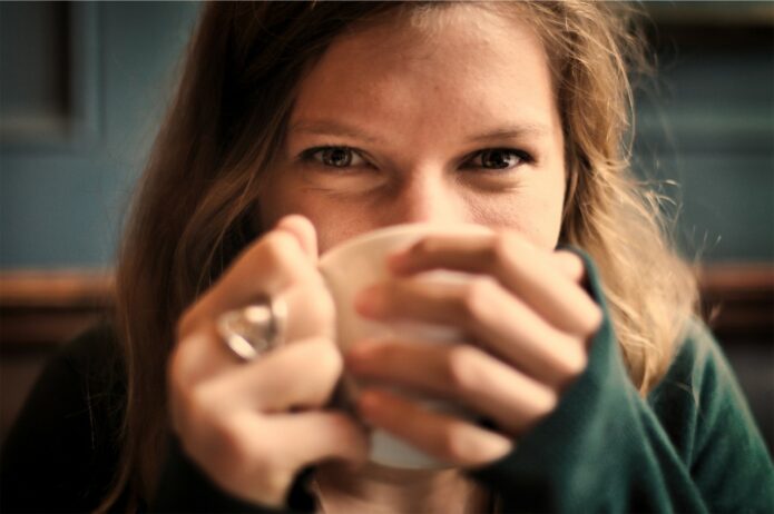 smile en kvinne med å holde kaffekoppen